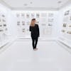 A woman stands in a modern gallery observing art exhibits in a bright and minimalistic museum room.