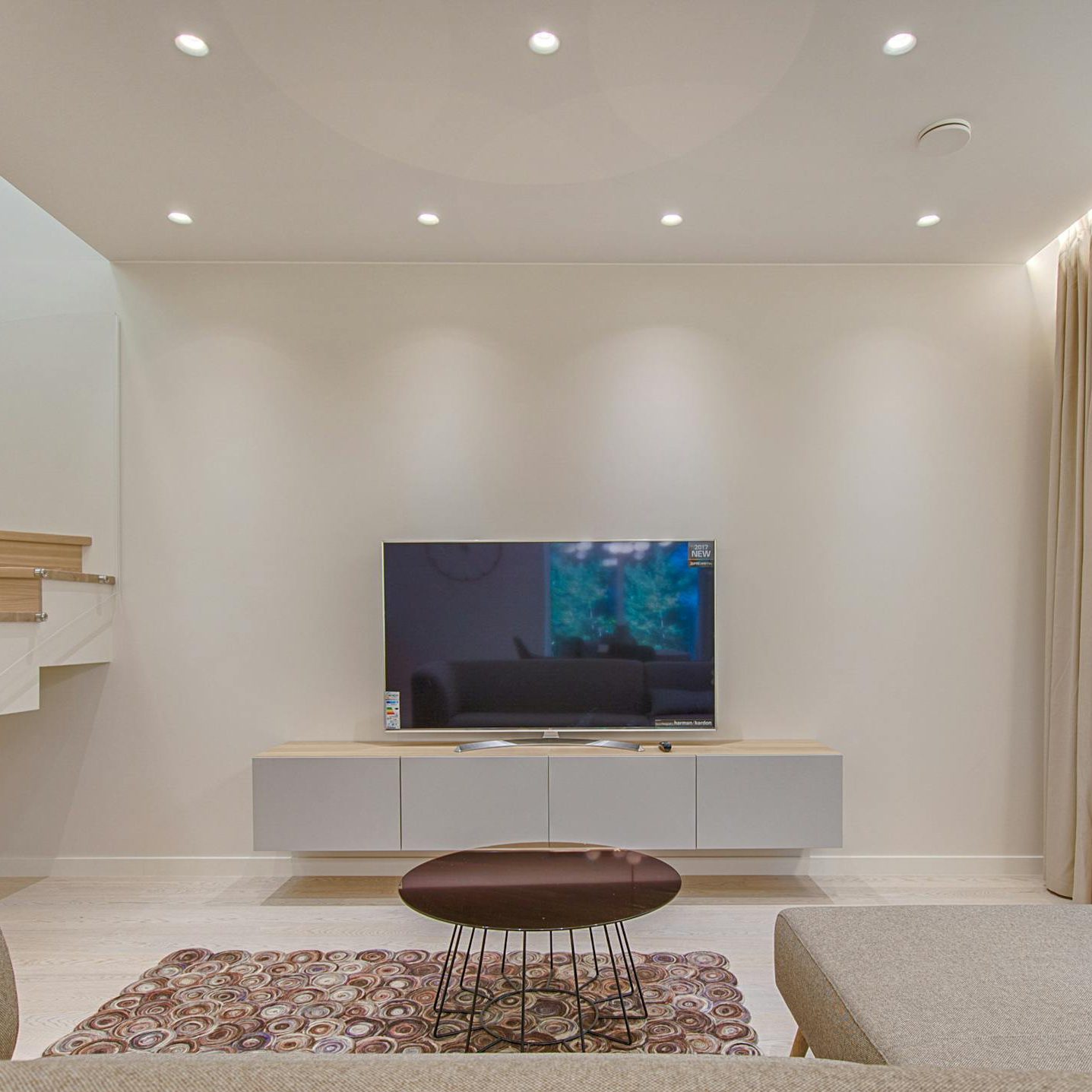 Contemporary living room with stylish sofa, TV, and staircase, offering a cozy interior design setting.