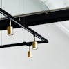 Stylish gold pendant lamps hang from a black metal frame in a modern, minimalist interior.